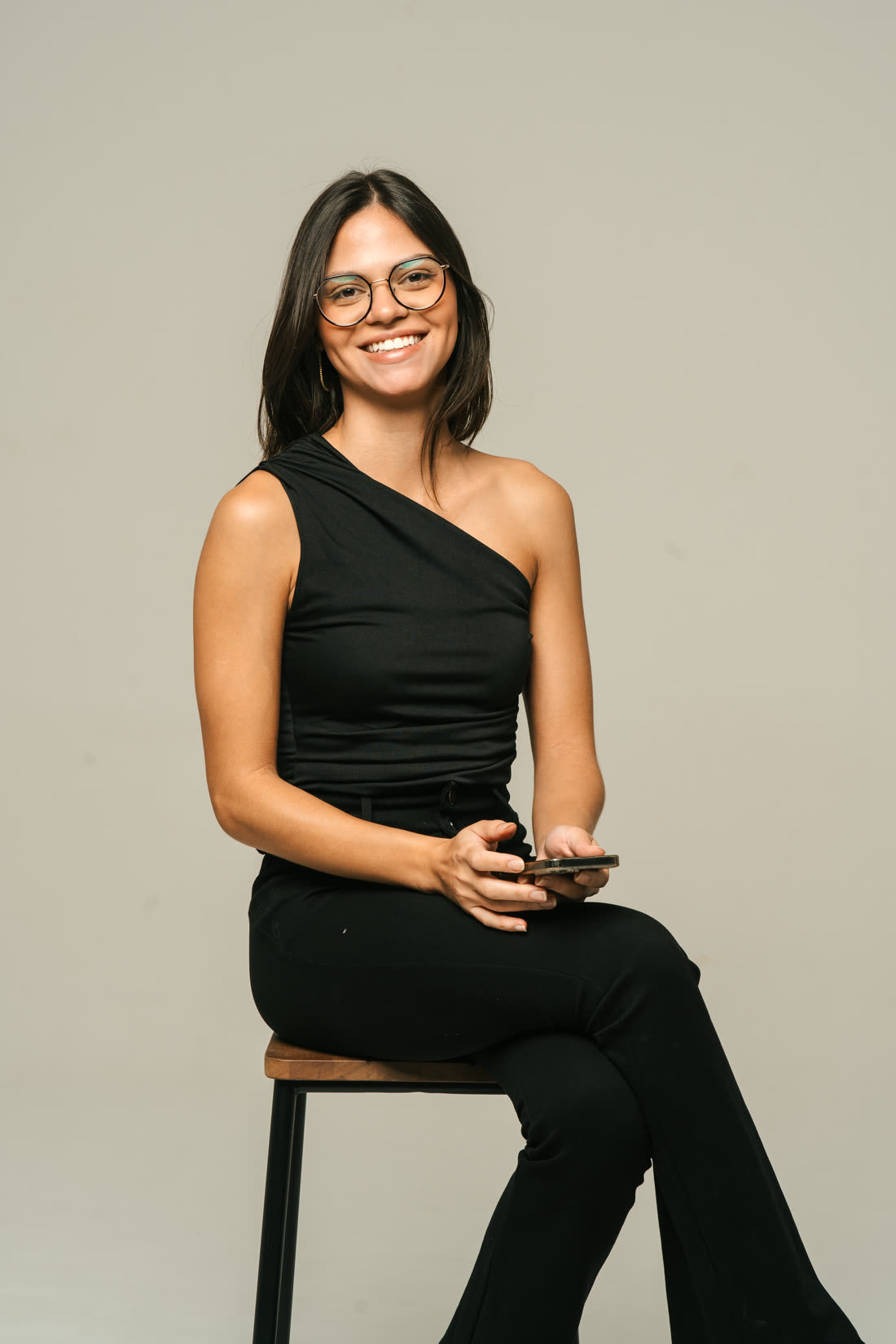Juliane Mattiello, storymaker, sentada segurando o celular
